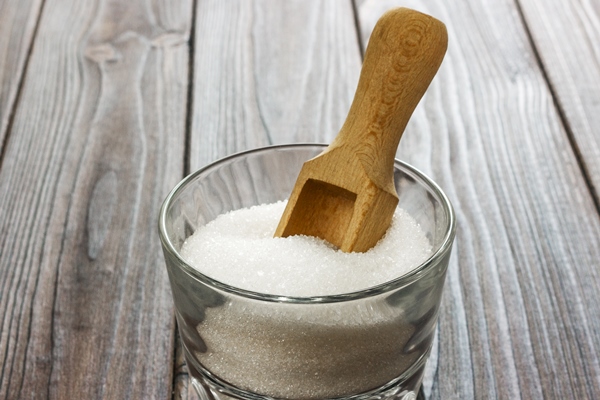white granulated sugar in white cup with wooden spoon on dark wooden background - Постные прянички из битого теста