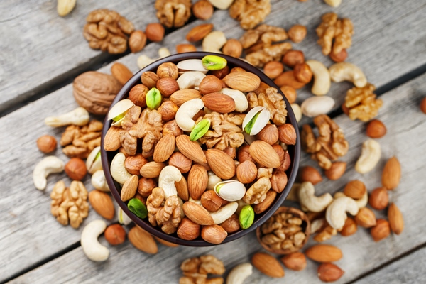 wooden bowl with mixed nuts on a wooden gray surface - Итальянский рождественский пирог "Панфорте"