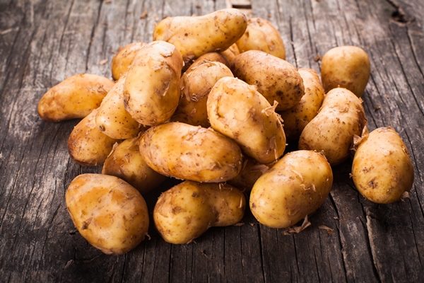 young potato heap on a wooden background - Печёный картофель с пряностями