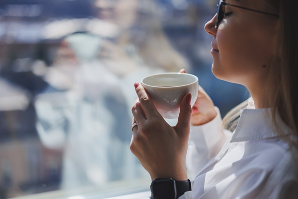 a woman in a white shirt with fragrant hot coffee in her hands closeup woman s hands with a cup of americano selective focus - Американо