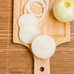bulb onions sliced on wooden cutting board top view - Киш с креветками и брокколи