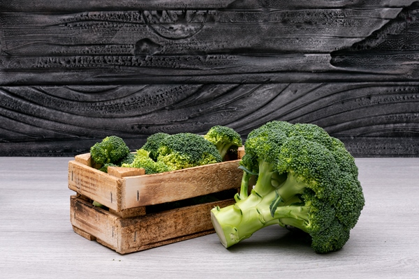bunches of broccoli in wooden box near the whole fresh broccoli - Запеканка с брокколи и кальмарами