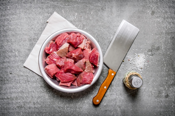 chopped raw meat with a butcher knife and salt on the stone table - Прозрачный мясной бульон