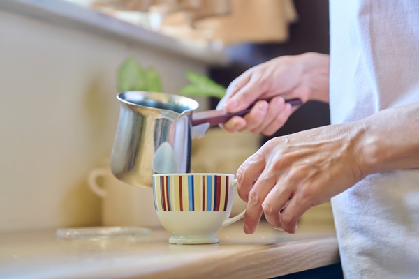 closeup of a woman s hands preparing coffee in an iron cezve - Кофе с сахаром и солью в турке