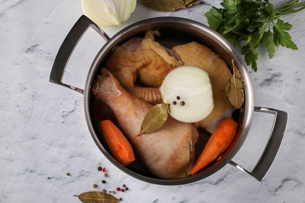 cooking broth from homemade chicken with pepper and bay leaf in a pan on a marble table vegetables are added to the broth onions and carrots healthy eating concept view from above - Правила приготовления заправочных супов