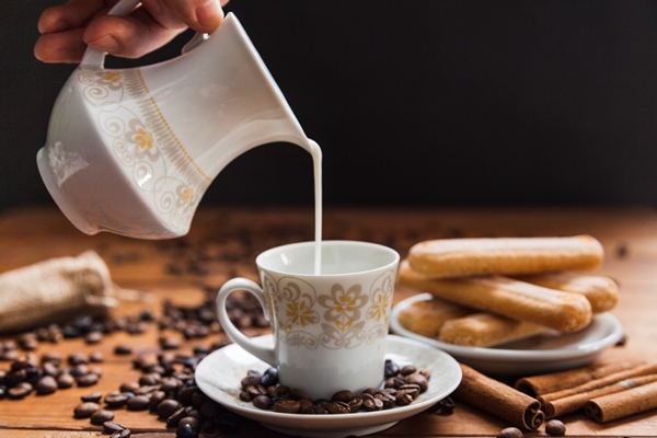 crop hand pouring milk into cup - Кофе бичерин