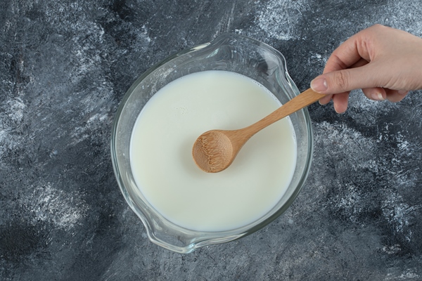 female hand holding spoon from bowl of milk - Суп-пюре картофельный с молоком