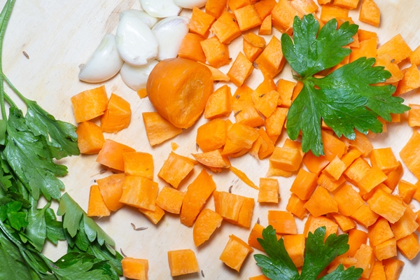 finely chopped carrots and parsley leaves on the table cooking soup ingredients summer food for a veggie lunch root crop on a cutting board - Щи зелёные с мясом и яйцом