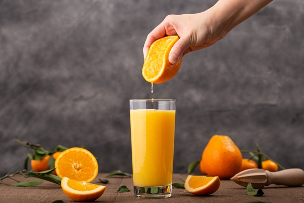 glass of orange juice and a person squeezing an orange in it - Безалкогольный глинтвейн с фруктово-ягодным соком
