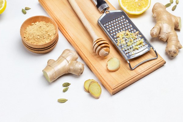 grater with grated ginger stick with honey on board ginger root dry ginger and lemon on table white background top view - Безалкогольный апельсиновый глинтвейн с имбирём