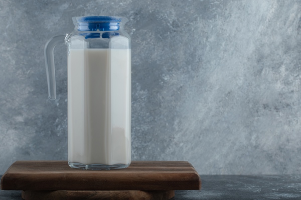jug of fresh milk on wooden board - Чай латте