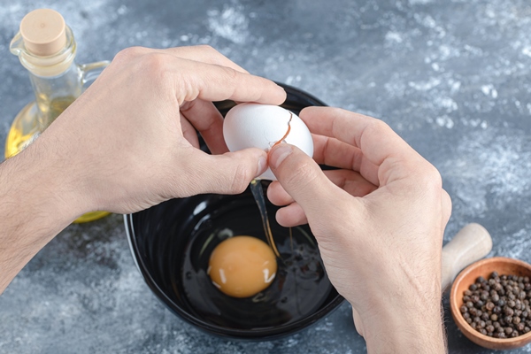 man hands breaking eggs in bowl over grey table 1 - Запеканка из макарон