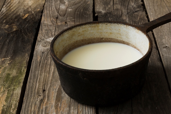 milk in the old vintage saucepan over the old wooden table - Горячий шоколад по-мексикански
