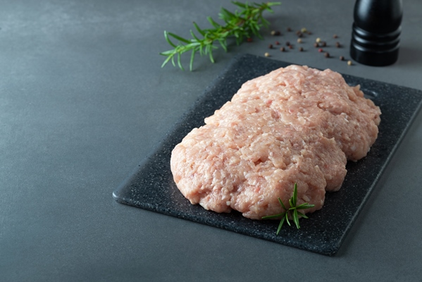 minced chicken or turkey meat on black board with rosemary and spices copy space - Бульон с куриными клёцками