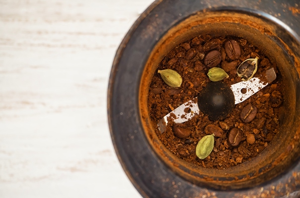 organic coffee beans with cardamom in coffee grinder close up - Кофе с кардамоном и сахаром