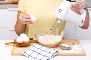 process of making dough for pancakes with ingredients on a light table eggs and flour are whipped with a mixer - Творожная запеканка с манной крупой