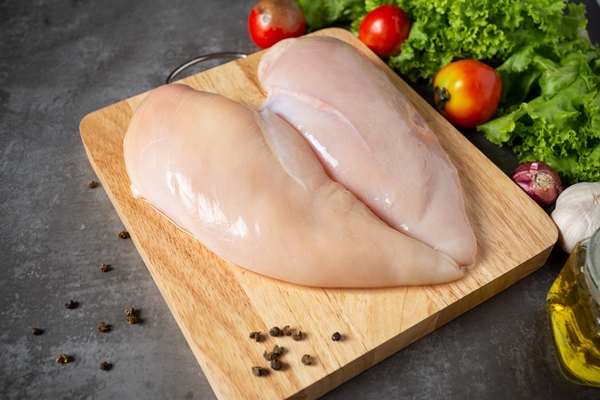 raw chicken breasts on wooden cutting board - Бульон с куриными клёцками