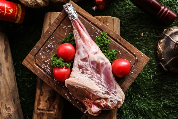 raw lamb leg on the wooden board prepared for cooking salt tomato greens top view - Чихиртма
