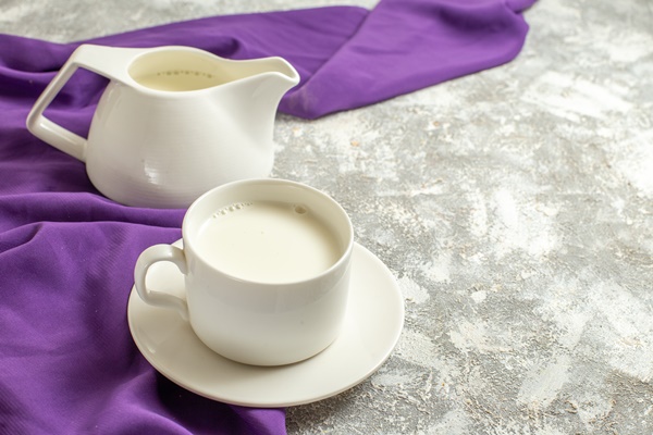 side close view of a cup of milk and a jug of milk on a purple napkin at the side on a marble backgound - Калмыцкий чай