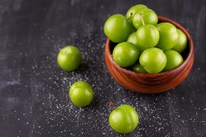 unripe green plums with salt on a black wooden table - Харчо