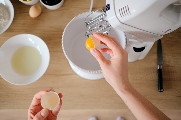 woman breaks chicken eggs in a bowl in the kitchen - Омлет "Пуляр"