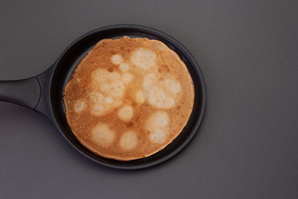 a delicious looking pancake cooking in a pan - Налистники с творогом и вареньем