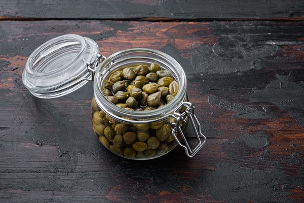 baby capers in marinated glass jar on old wooden table - Постный соус с каперсами