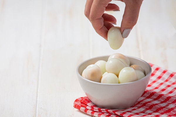 boiled quail eggs on the white wooden surface - Салат "Оливье"