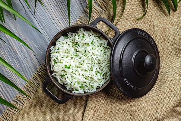boiled rice with herbs in a pan on a wooden table - Салат из крабовых палочек с рисом