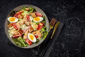caesar salad with chicken on a black background top view - Салат "Цезарь"