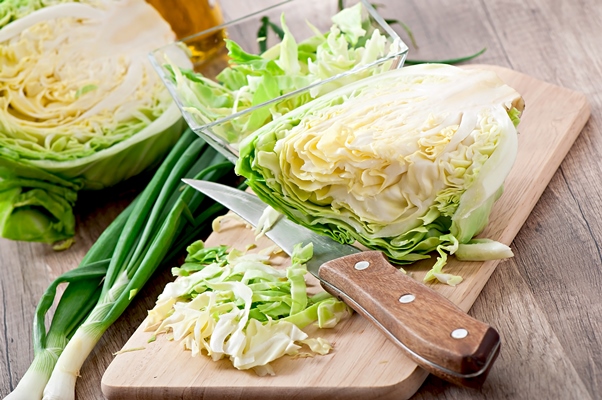 cutting cabbage on a wooden board - Баранина тушёная с овощами