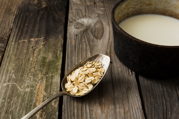 fresh oats in the rustic old spoon and milk in the saucepan over the old wooden table - Молочный овсяный суп