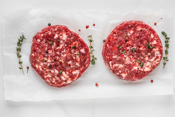 fresh raw minced meat beef burgers patties on white background with spices and herbs for cooking on white background top view - Правила выбора и приготовления мяса