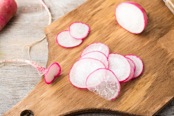 fresh sliced radish on a cutting board on a wooden table rustic style top view - Салат из редиса со сметаной