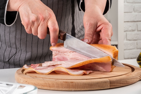 front view of chef cutting bacon strips - Спагетти в сливочном соусе с ветчиной