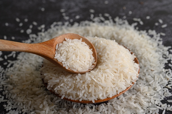 milled rice in a bowl and a wooden spoon on the black cement floor - Рисовая молочная каша