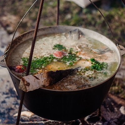 millet porridge with meat potatoes onion garlic herbs salt and spices cooking ukrainian national dish in metal pot on an open fire - Кулеш со свининой