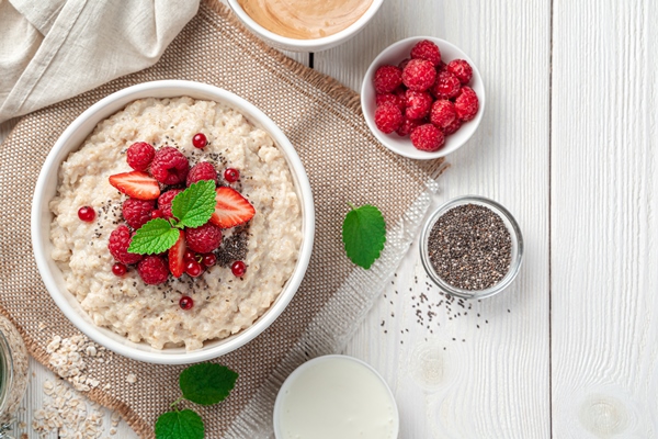 oatmeal porridge with fresh berries chia seeds and mint on a light background - Овсяная молочная каша