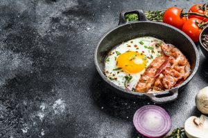 pan of fried eggs with bacon and fresh tomato - Яичница с беконом