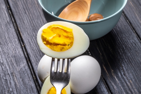 side view of boiled egg half with fork on wooden rustic - Винегрет из фаршированного перца с картофелем