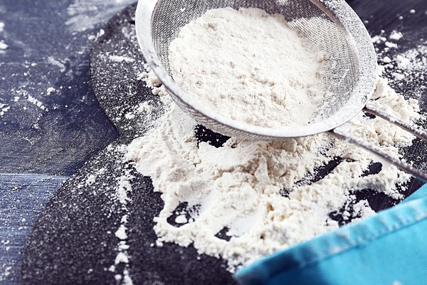 sifting flour through sieve on wooden table closeup - Тушёное мясо с макаронами
