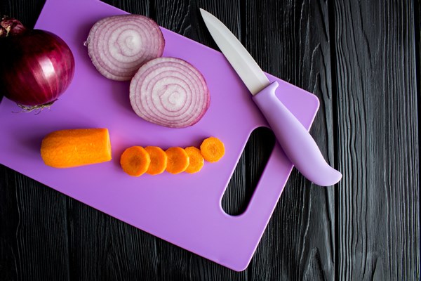 sliced carrots and onion on the violet cutting board on the black wooden background top view - Молочный суп с лососем и рисом