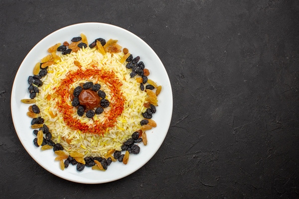 top view delicious plov with oil and raisins inside plate on the dark space - Гурийский плов