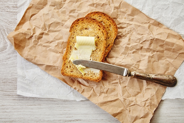 top view of two slices of rye dry bread as toast with butter for breakfast with vintage knife on it everything on craft paper 1 - Бутерброды на поджаренном хлебе