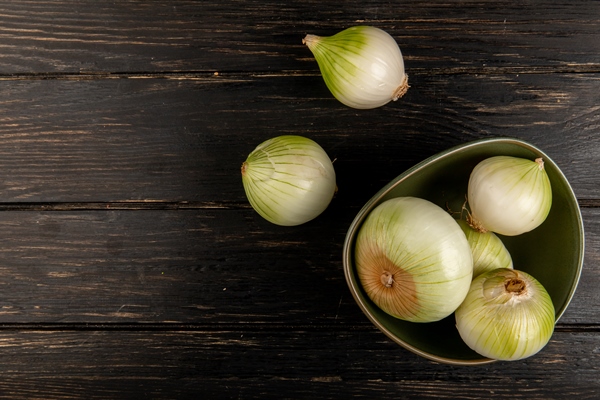 top view of white onions in bowl on wooden background with copy space - Сельдь под шубой