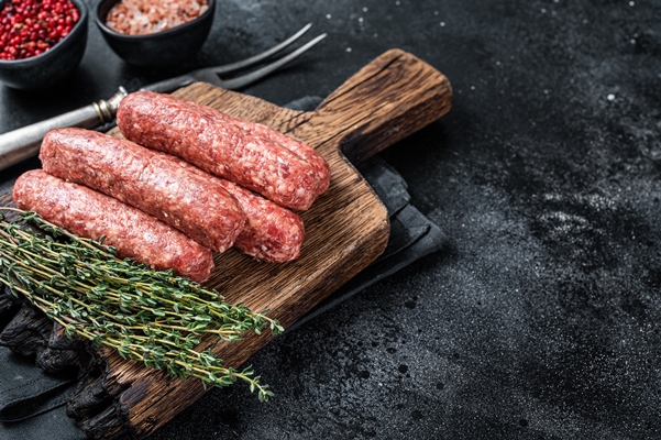 uncooked raw beef and lamb meat kebabs sausages on a wooden board black background top view copy space - Зразы из телятины
