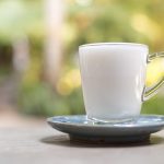 white hot milk in a glass placed on a table with a green backdrop - Суп-пюре из моркови на молоке