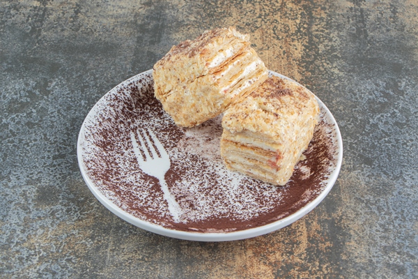 a white plate with two pieces of napoleon cake and cocoa powder - Монастырская кухня: архиерейская солянка, постный "Наполеон" (видео)
