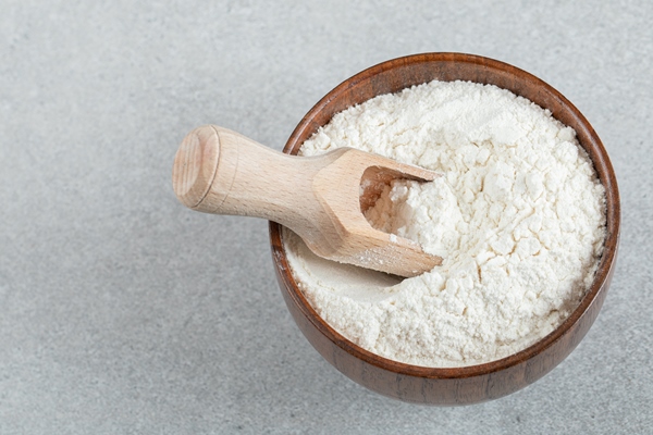 a wooden bowl of flour and wooden spoon - Соус белый к паровой рыбе