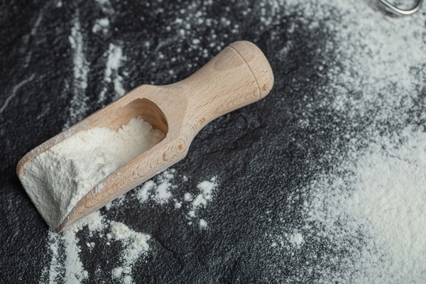 a wooden spoon with flour on black - Монастырская кухня: рисовые котлеты с грибным соусом, овсяное печенье